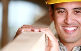 Construction worker holding wood, smiling