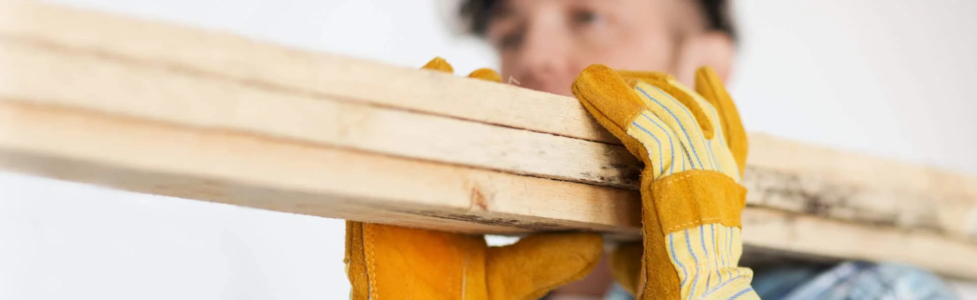 close up of male in gloves carrying wooden boards